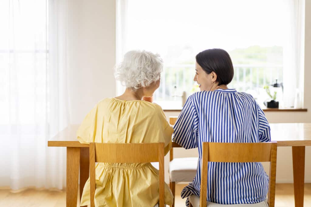 Two Asian women are sitting on chairs and talking
