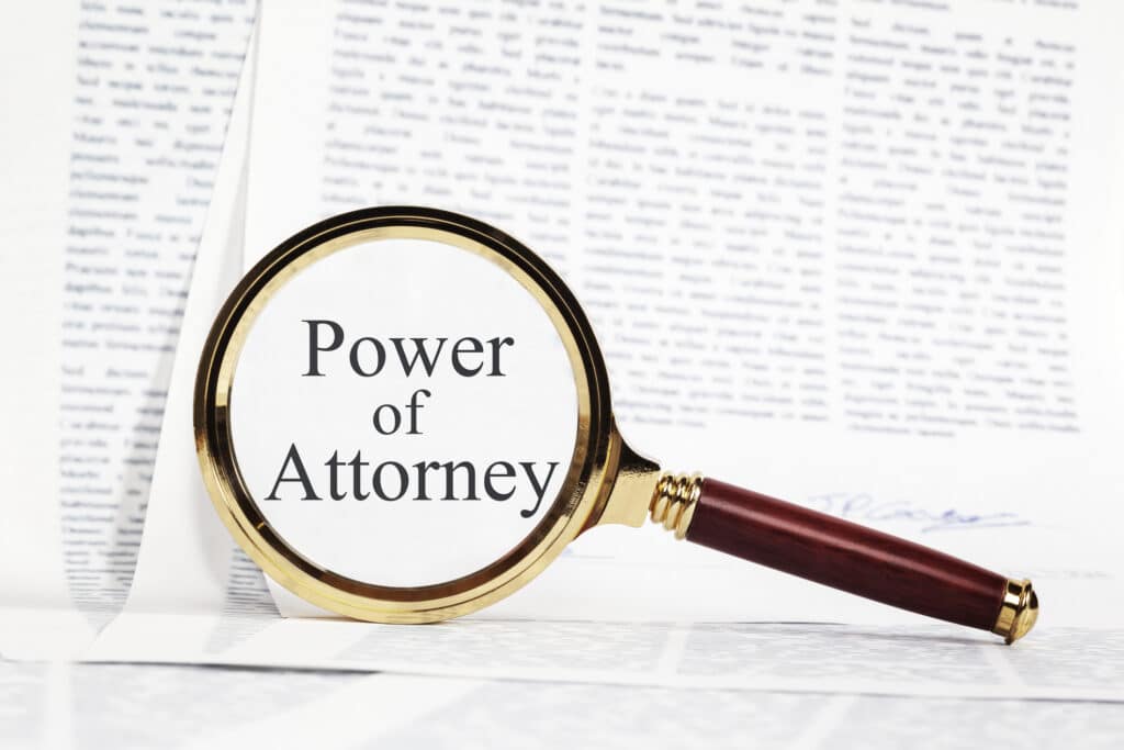 Paperwork representing a Power of Attorney, with a magnifying glass over, highlighting Power of Attorney.